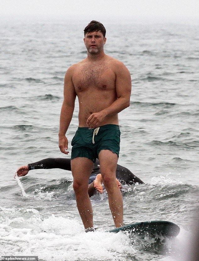 Colin Jost models his buff torso as he is seen surfing off the coast in
