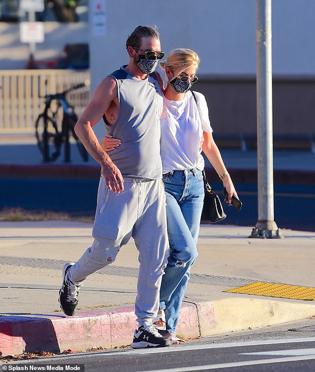 Megan Blake Irwin and Skeet Urlich take off their matching his 'n her masks to pash at a table ...